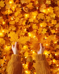 Hands holding vibrant autumn leaves over a background of golden leaves with soft glowing lights.
