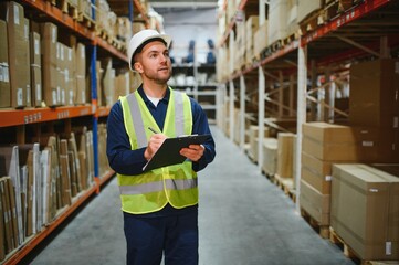 Portrait of warehouseman with clipboard checking delivery, stock in warehouse. Warehouse worker...