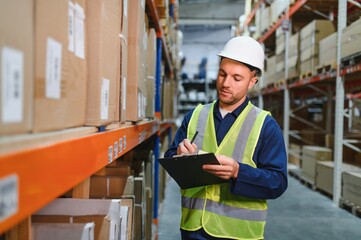 Portrait of warehouseman with clipboard checking delivery, stock in warehouse. Warehouse worker...