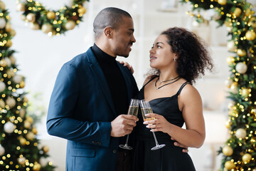 Cheers. Happy african american couple drinking champagne near Christmas tree at home, toasting holidays. High quality photo