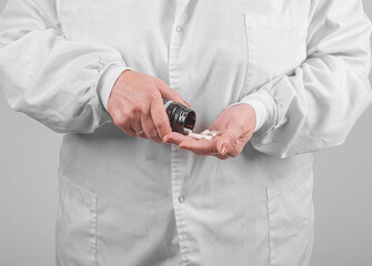 Bottle with medical capsules in the hands of a person in a white coat.
