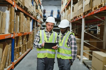 Two warehouse workers checking and controlling boxes in warehouse, Professional warehouse workers