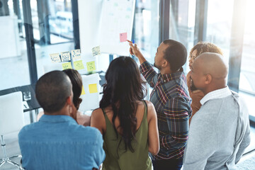 Obraz premium Collaboration, glass and pointing with business people in office for coaching, meeting or planning. Marker, training or workshop with employee team at work and sticky notes on window for development