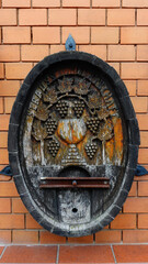 Intricate Wooden Fountain Featuring Grapevine Carvings on a Brick Wall