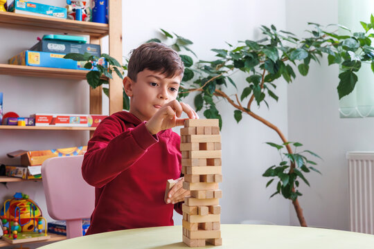 A boy plays Jenga in a cozy children's room. the topic of cognitive development, logical thinking, motor skills, mental health, autistic support and inclusive education for children with special needs