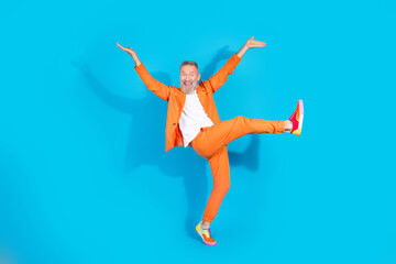 Full length photo of trendy eccentric man dance rejoice wear orange suit isolated on blue color background