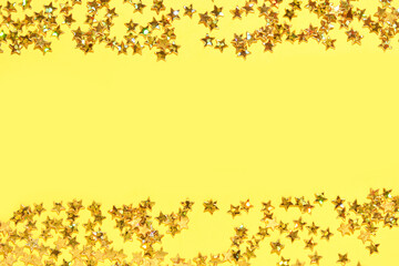 Shimmering gold star confetti on vibrant yellow background for festive celebrations and creative designs.