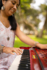 Woman musician playing a melody on her harmonium in the park