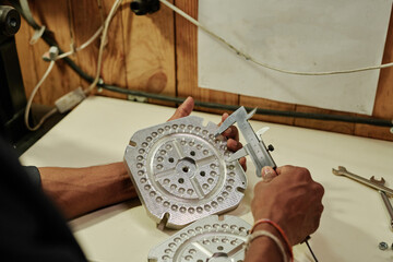Hands of young unrecognizable technician or worker of plastic recycling factory measuring press mold with caliper