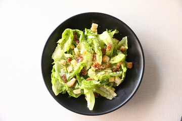 Caesar salad with croutons and parmesan cheese in black dish on white background italian food,...