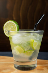 Typical drink from Brazil called Caipirinha, made with lemon and sugar with cachaça. Favorite cocktail of Brazil, isolated over wood texture.