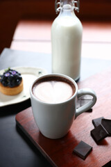 Hot chocolate with art in a white glass cup . The chocolate is sprinkled with some grated dark chocolate.