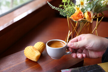 Espresso coffee with white cup on wooden table and Hand holding a white cup of hot espresso coffee