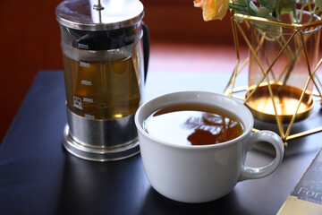 A cup of hot tea with black background, wood background, with a cup of hot tea in hand ,warm photo.