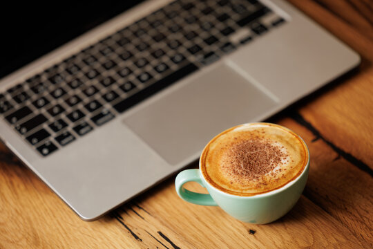 Cappuccino coffee next to the work laptop.