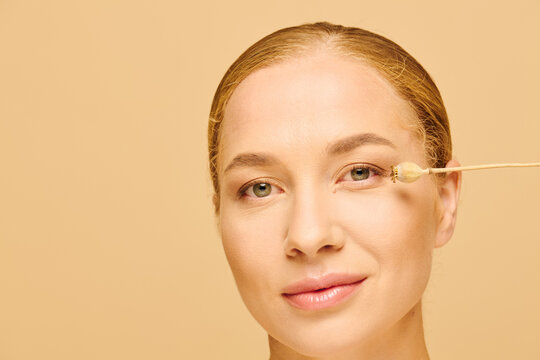 A young beautiful plus size woman gently applies skincare to her face, showcasing self care.