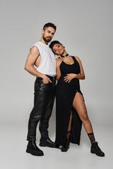 A couple stands close together, exuding affection and confidence in their fashionable outfits.
