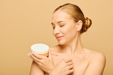 A cheerful young woman delicately holds a skincare container while savoring the moment.