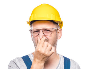Dissatisfied construction worker holding his nose closed has disgusting expression on face,...