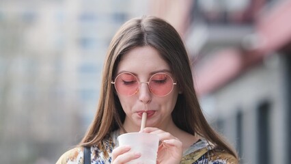 Pensive happy woman sipping a milkshake in the street