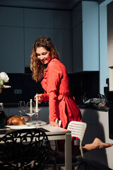 Woman housewife in red dress cooking a romantic dinner in the kitchen