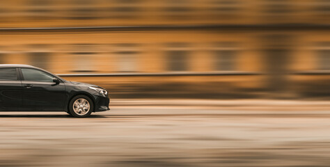 Fast moving car. Side view of the front of a black car, blurred background with free space for text, copy space