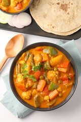 Mix vegetable curry - Indian main course recipe contains Carrots, cauliflower, green peas and beans and served in ceramic ware with Chapati ,Indian flat bread , roti