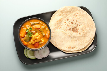 Mix vegetable curry - Indian main course recipe contains Carrots, cauliflower, green peas and beans and served in ceramic ware with Chapati ,Indian flat bread , roti