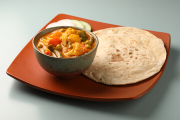Mix vegetable curry - Indian main course recipe contains Carrots, cauliflower, green peas and beans and served in ceramic ware with Chapati ,Indian flat bread , roti