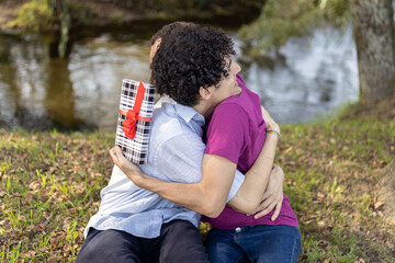 Gay couple embracing in park after exchanging gifts on anniversary