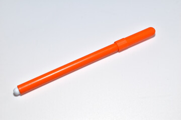 An orange felt-tip pen lies on a white background.