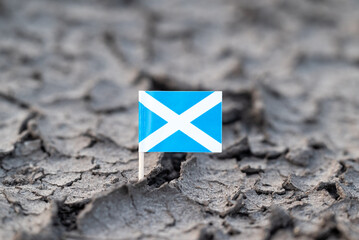 Flag of Scotland in dry cracked ground. Concept of drought in Scotland, hot rainless weather