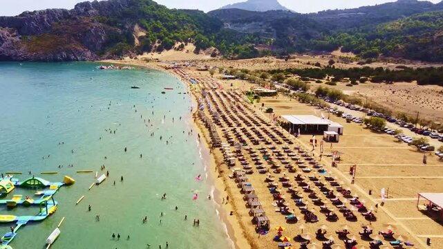 Aerial view of sandy beach of Tsambika with tourists swimming in beautiful clear sea water. Greece Europe