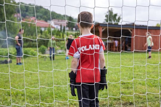 Chłopiec na bramce w koszulce z napisem Polska (ang. Poland).