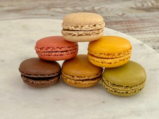 Colorful macarons on the marble plate on the wooden background 