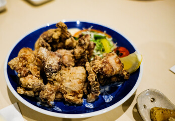 close up of Japanese deep fried chicken in a blue plate with copy space
