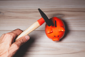 orange piggy bank on wooden table with hammer