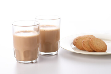 Indian Chai or Indian tea served in a traditional tea glass with snacks 