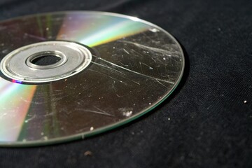 A focused shot of a scratched DVD isolated on black, digital imperfection, digital video defect, video quality issue, disc damage, optical fault