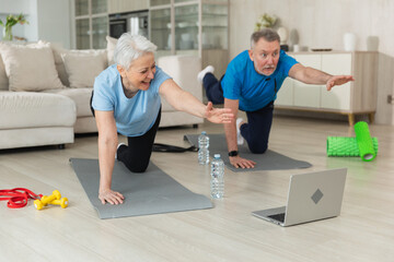 Fitness workout training. Senior adult mature healthy fit couple doing sports exercise on yoga mat...