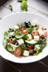 Healthy Salad with Feta Cheese, Black Olives, Cucumber and Cherry Tomatoes. Wooden background. Close up.