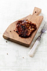 Grilled pork steak on wooden background. Copy space.