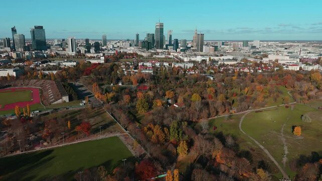 A panoramic, drone clip of Warsaw skyline from the perspective of Pole Mokotowskie in autumn - backward movement.