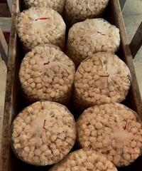 Multiple large plastic bags filled with popcorn, neatly arranged in a wooden crate.