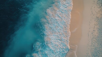 Aerial view of turquoise ocean waves crashing on a white sandy beach.