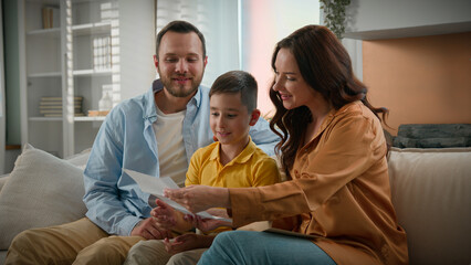 Happy Caucasian family mother father mom dad parents beloved son kid boy receive paper letter read...
