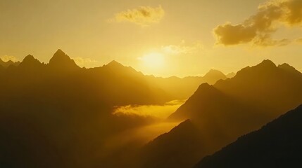 Golden sunset over a range of mountains, with clouds silhouetted against the sky.