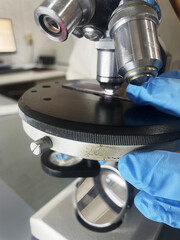Laboratory technician looks at a blood sample through a microscope, equipment and scientific experiments in the laboratory, chemicals for research and analysis of the sample, global pandemic