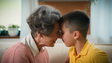 Happy loving elderly retired woman grandmother play with child kid boy grandson at home rubbing noses together expressing tenderness tender relationship enjoying affection two age generations family