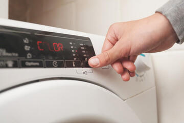 A person presses a button to select the spin cycle of the washing machine.